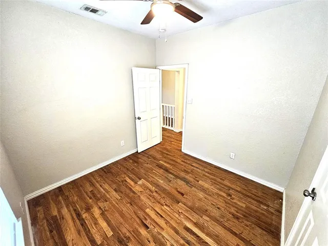 a view of a room with wooden floor and a ceiling fan