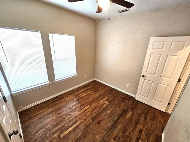 a view of empty room with wooden floor and fan