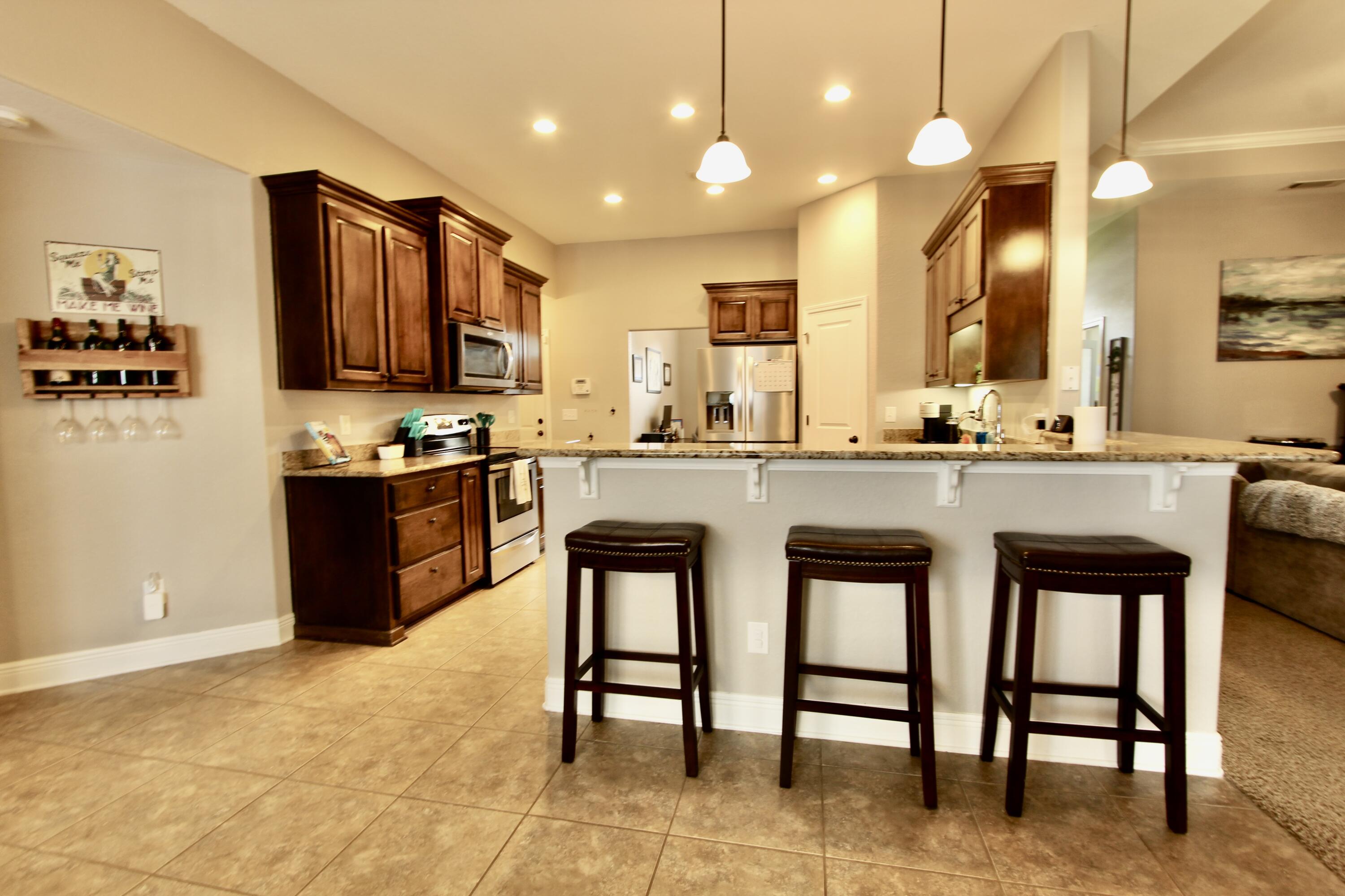 502 Vale Loop Crestview, FL 32536 - Photo 12 of 53 a kitchen with stainless steel appliances kitchen island granite countertop a table chairs sink and cabinets