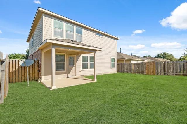 a view of a house with a yard and wooden fence
