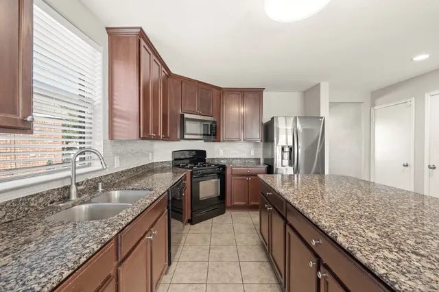a kitchen with stainless steel appliances granite countertop a sink stove and refrigerator