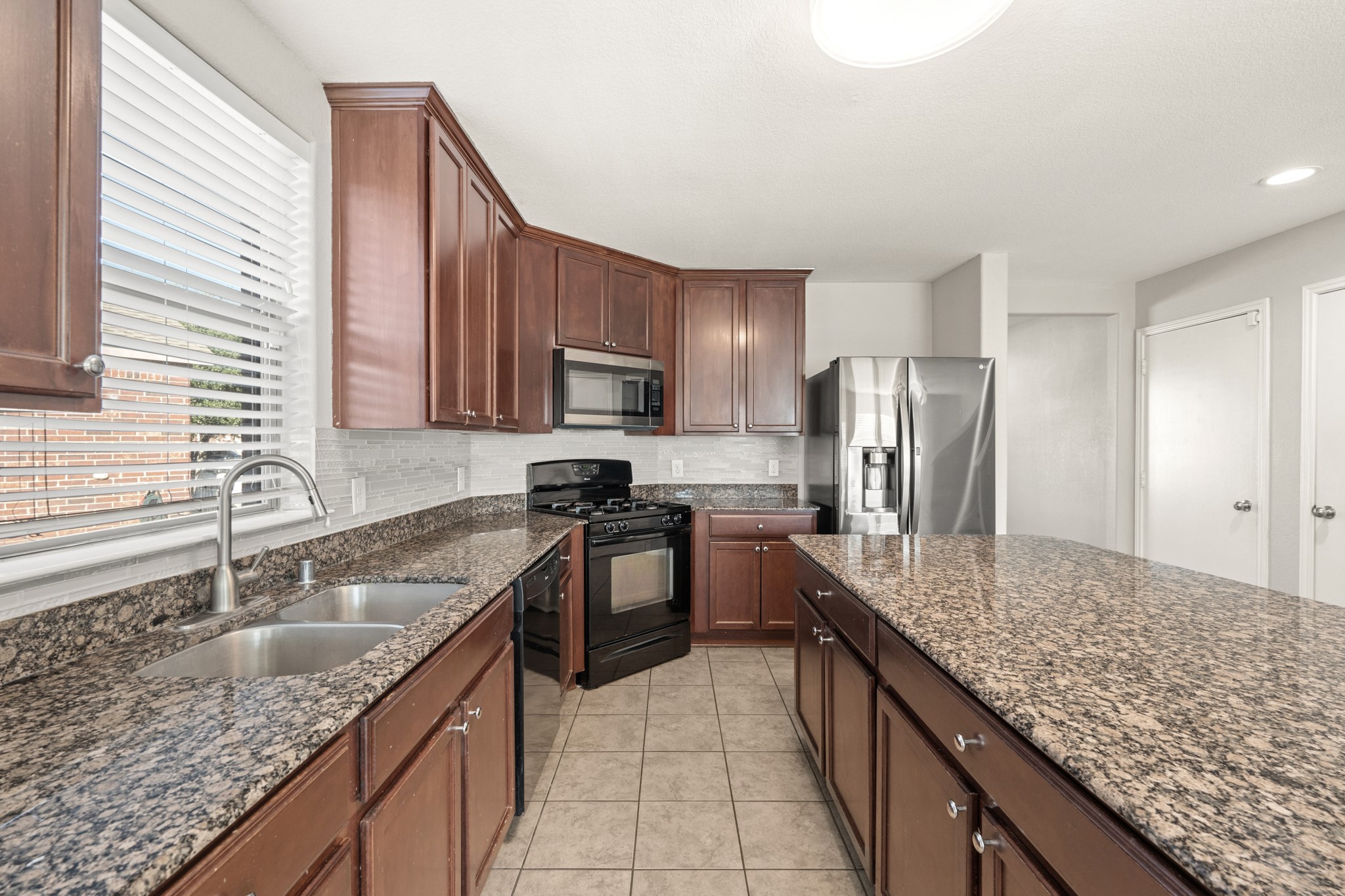 21359 Bandera Ranch Lane Katy, TX 77449 - Photo 9 of 31 a kitchen with stainless steel appliances granite countertop a sink stove and refrigerator