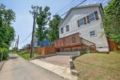 a view of a house with a yard plants and large tree