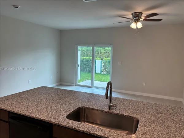 a kitchen with kitchen island granite countertop a sink and a refrigerator