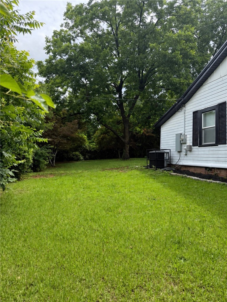 112 Simmons Street Anderson, SC 29625 - Photo 3 of 26 A spacious, verdant yard extends towards mature trees, offering ample outdoor living potential.