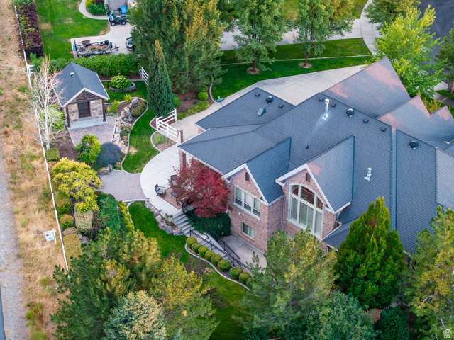 875 South 1250th Street East Mapleton, UT 84664 - Photo 15 of 54 Expansive property featuring a brick and siding exterior, a dark shingle roof, paved driveways, a detached stone outbuilding with a porch, and diverse landscaping with mature trees and shrubs