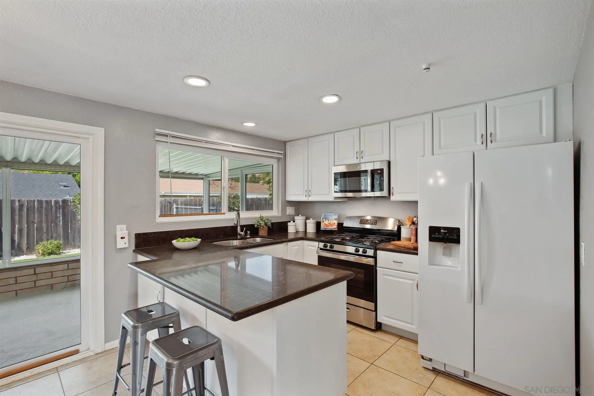 13432 Carriage Road Poway, CA 92064 - Photo 11 of 27 a kitchen with granite countertop stainless steel appliances a stove a sink a refrigerator white cabinets and wooden floor
