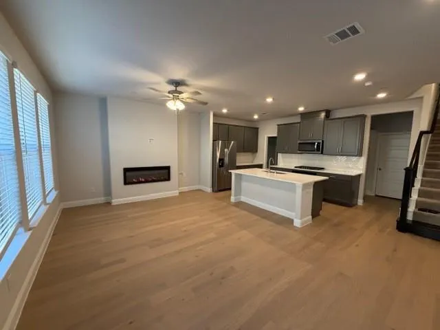 a large white kitchen with kitchen island a stove a sink dishwasher and a refrigerator with wooden floor