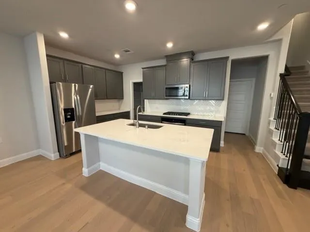 a kitchen with kitchen island a sink stainless steel appliances and cabinets