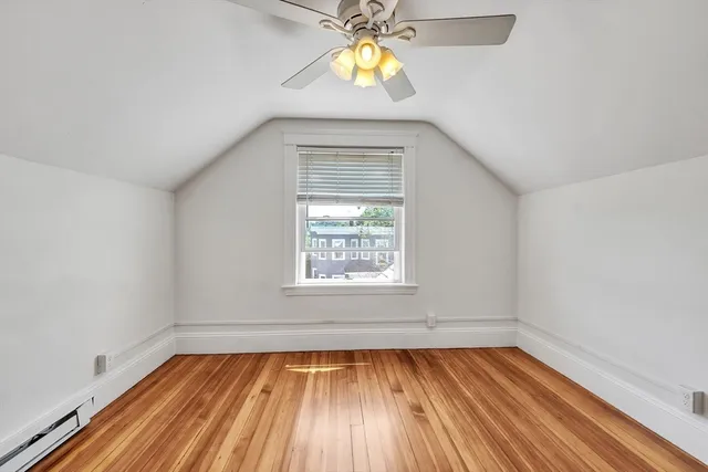 an empty room with wooden floor windows and a chandelier fan