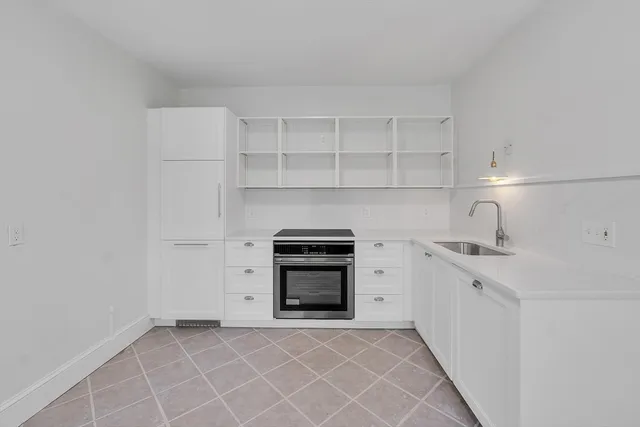 a kitchen with white cabinets and appliances
