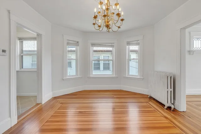 a view of empty room with window and wooden floor