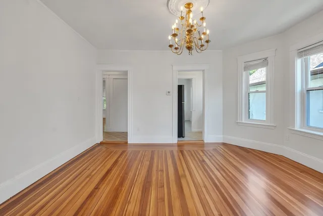 a view of a room with wooden floor and chandelier