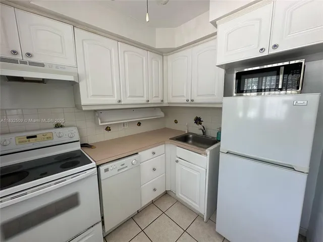 a kitchen with white cabinets and white appliances
