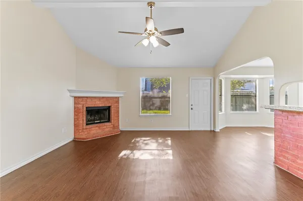 a view of an empty room with wooden floor fireplace and a window