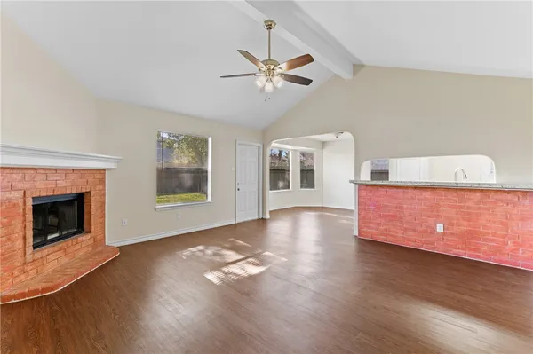 a view of a livingroom with wooden floor a fireplace and windows