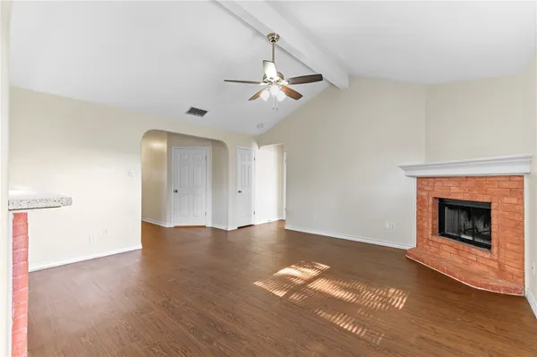 a view of an empty room with wooden floor fireplace and a window