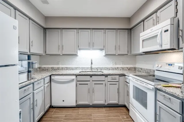 a kitchen with stainless steel appliances granite countertop a sink and cabinets with wooden floors
