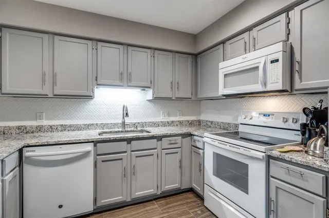 a kitchen with granite countertop white cabinets and white appliances