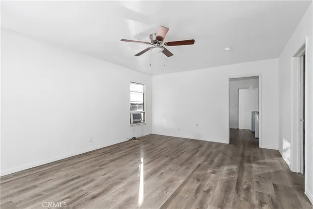 a view of empty room with wooden floor and ceiling fan