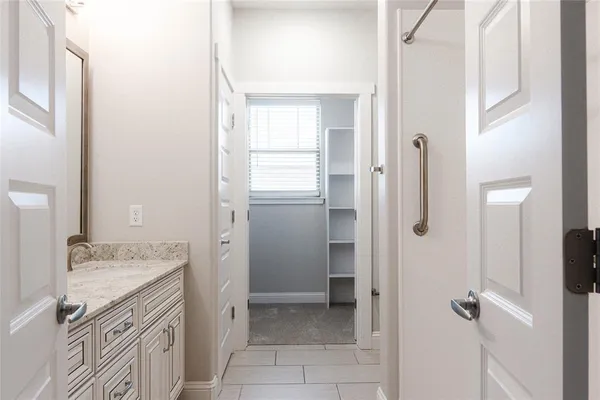a bathroom with a granite countertop sink a mirror and a shower