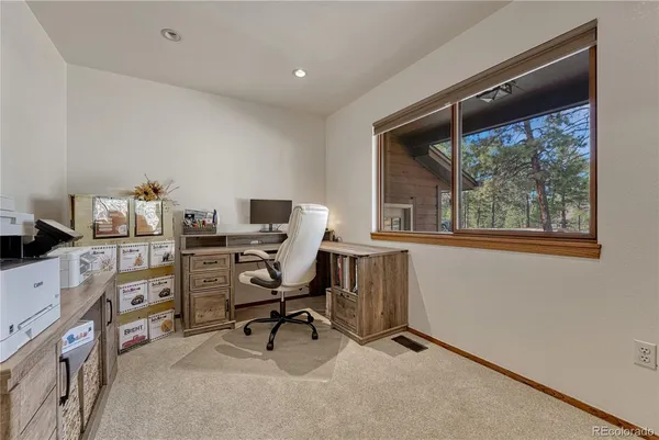 a view of a workspace with furniture and a window