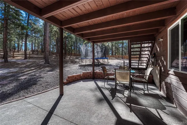 a view of a patio with table and chairs potted plants with floor to ceiling window