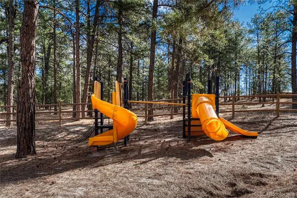 a view of a park with slide and wooden fence