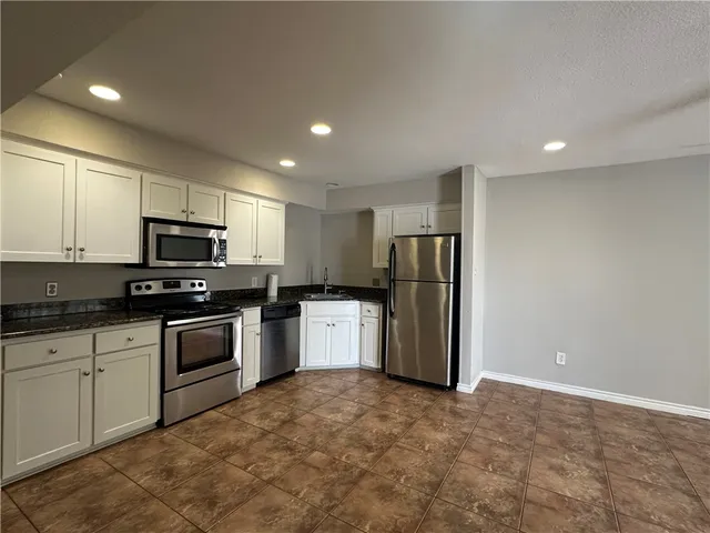 a kitchen with stainless steel appliances granite countertop a refrigerator and a stove top oven