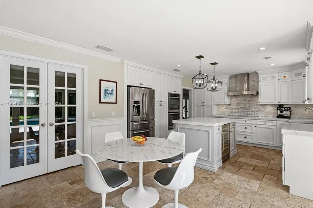 a kitchen with stainless steel appliances kitchen island granite countertop a dining table chairs and white cabinets