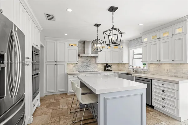 a kitchen with a sink a center island stainless steel appliances and cabinets