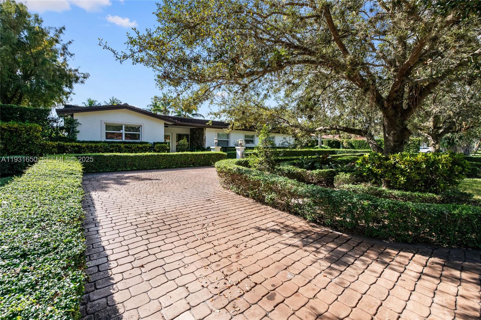7360 Southwest 115th Street Pinecrest, FL 33156 - Photo 4 of 49 a front view of a house with a yard and trees