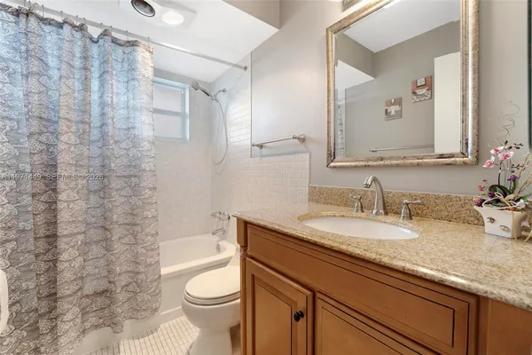 a bathroom with a granite countertop sink toilet and a mirror