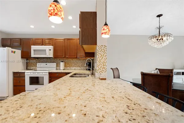 a kitchen with stainless steel appliances kitchen island granite countertop a refrigerator and a stove top oven