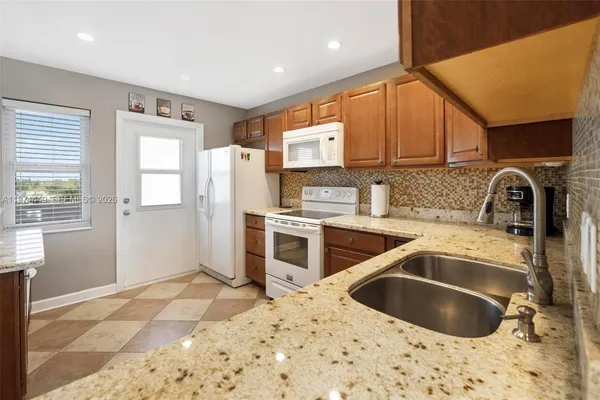 a kitchen with granite countertop a sink a counter top space cabinets and stainless steel appliances
