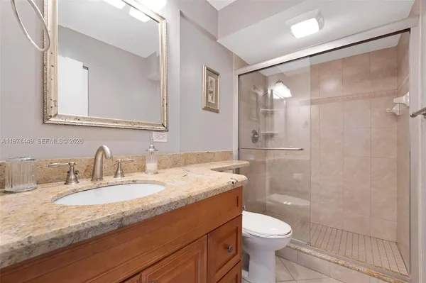 a bathroom with a granite countertop sink toilet and shower