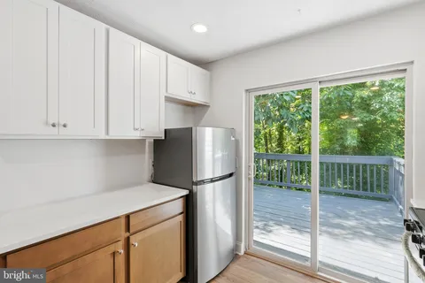 a kitchen with a refrigerator a stove and white cabinets with wooden floor