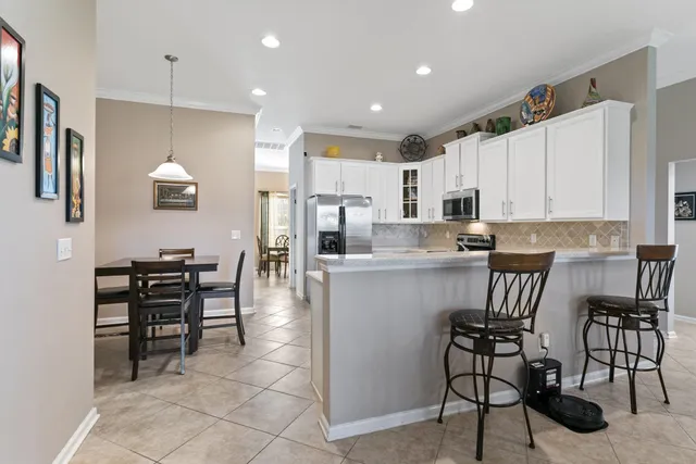 a kitchen with stainless steel appliances a dining table chairs and refrigerator