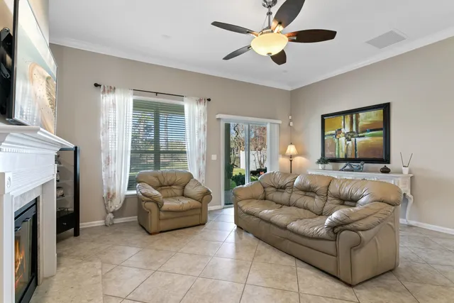 a living room with stainless steel appliances furniture a fireplace and a ceiling fan