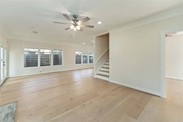 an empty room with wooden floor fan and windows