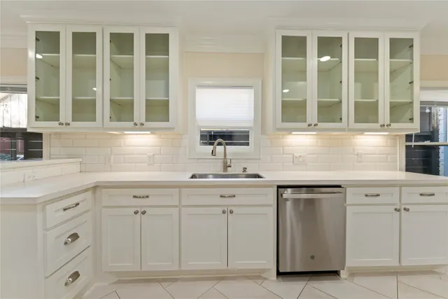 a kitchen with white cabinets and sink