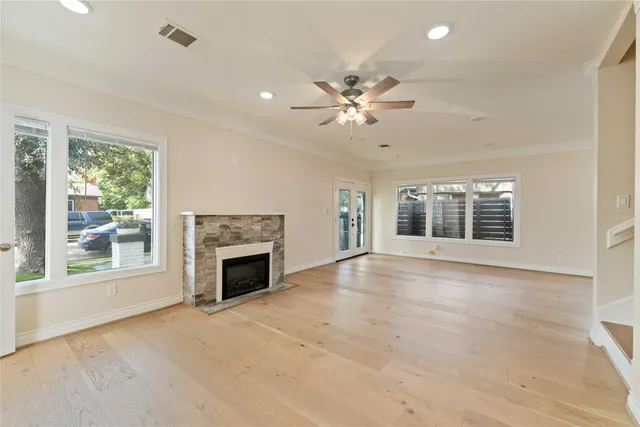 an empty room with windows fireplace and fan