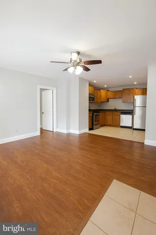 a view of an empty room with window and a kitchen