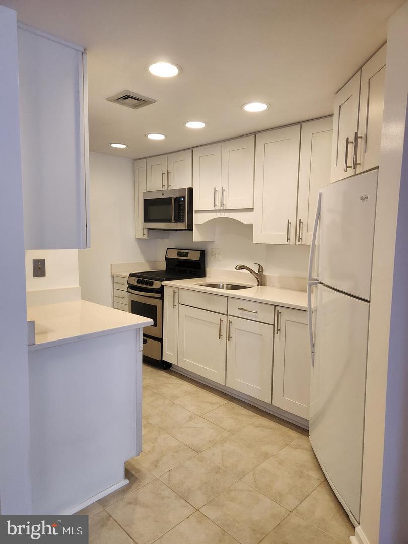 2725 Connecticut Avenue Northwest, Unit 406 Washington, DC 20008 - Photo 8 of 24 a kitchen with white cabinets and white stainless steel appliances