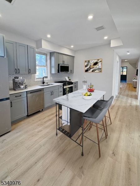 445 Grove Street, Unit 2 Irvington, NJ 07111 - Photo 10 of 11 a open dining room with stainless steel appliances a dining table wooden floor furniture and a kitchen view