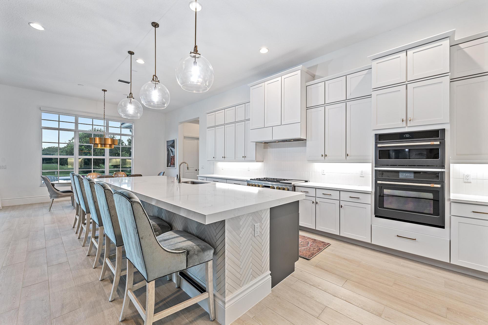 10096 Calabrese Trail Jupiter, FL 33478 - Photo 23 of 58 a kitchen with stainless steel appliances a stove a sink a dining table and chairs with wooden floor