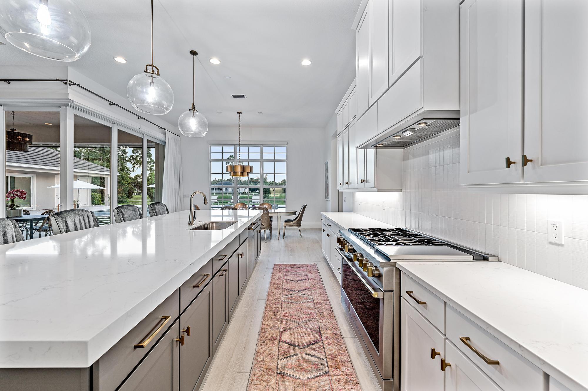 10096 Calabrese Trail Jupiter, FL 33478 - Photo 24 of 58 a kitchen with kitchen island a large counter space a sink appliances and cabinets