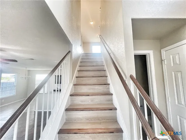 a view of staircase with lots of frames on wall and wooden floor