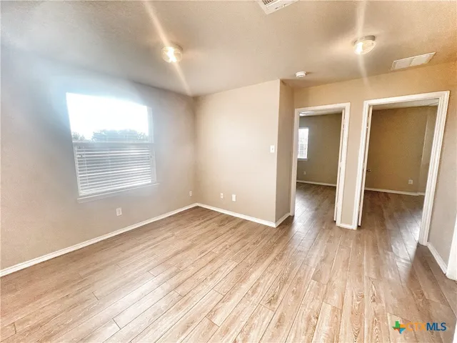 an empty room with wooden floor and windows