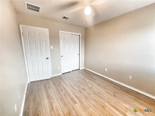 an empty room with wooden floor and a ceiling fan